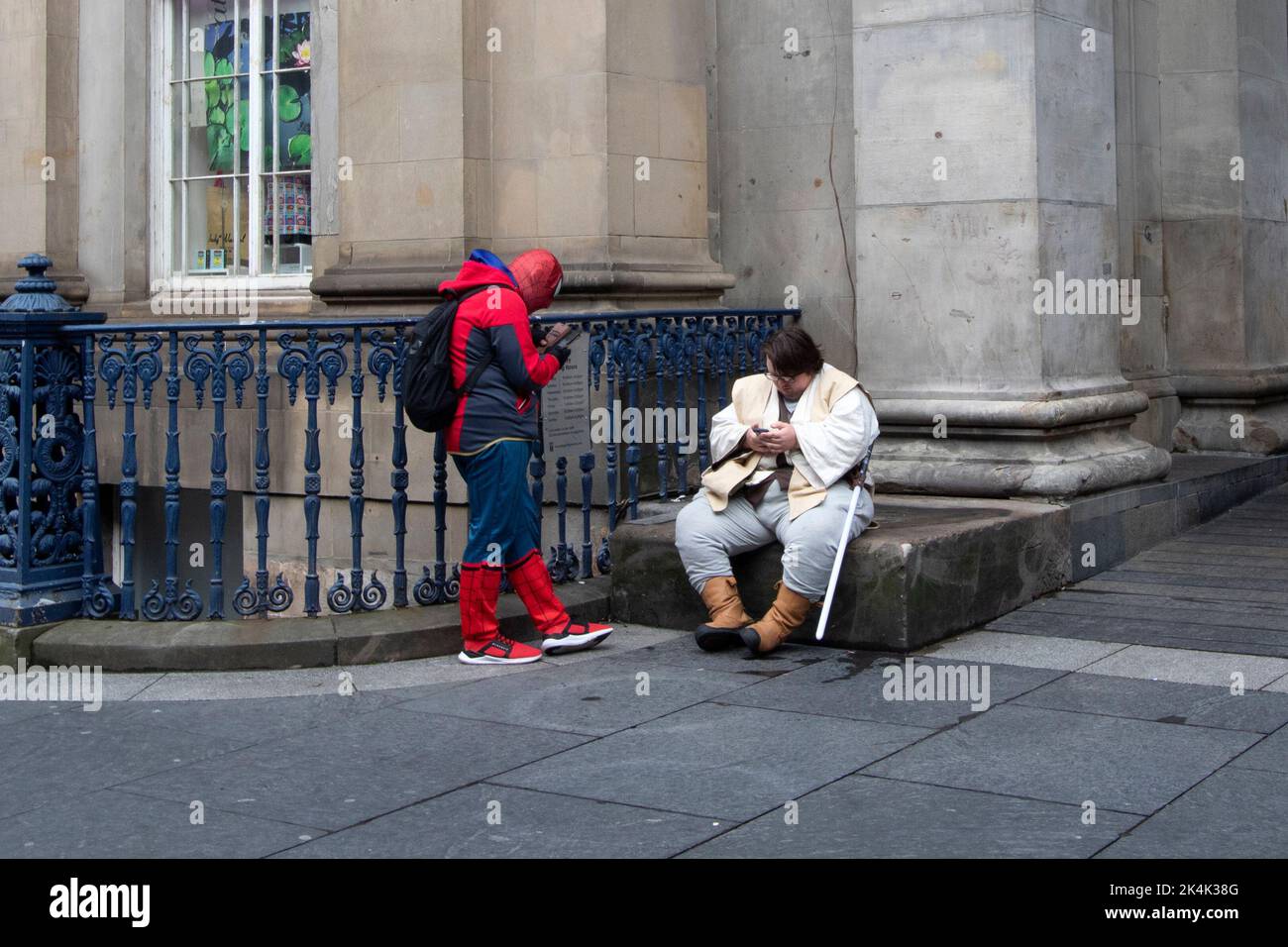 Spider man and Obi-wan Kenobi check their phones, outside the Gallery of Modern Art, Glasgow, Glasgow Scotland UK Stock Photo