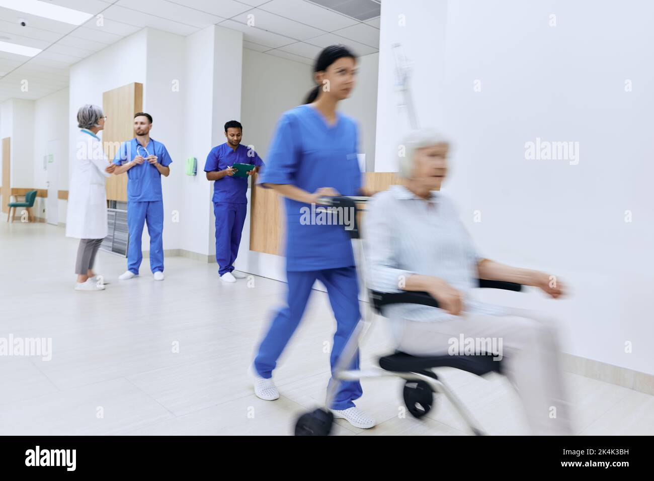 Doctors are talking, nurse is pushing wheelchair with elderly patient