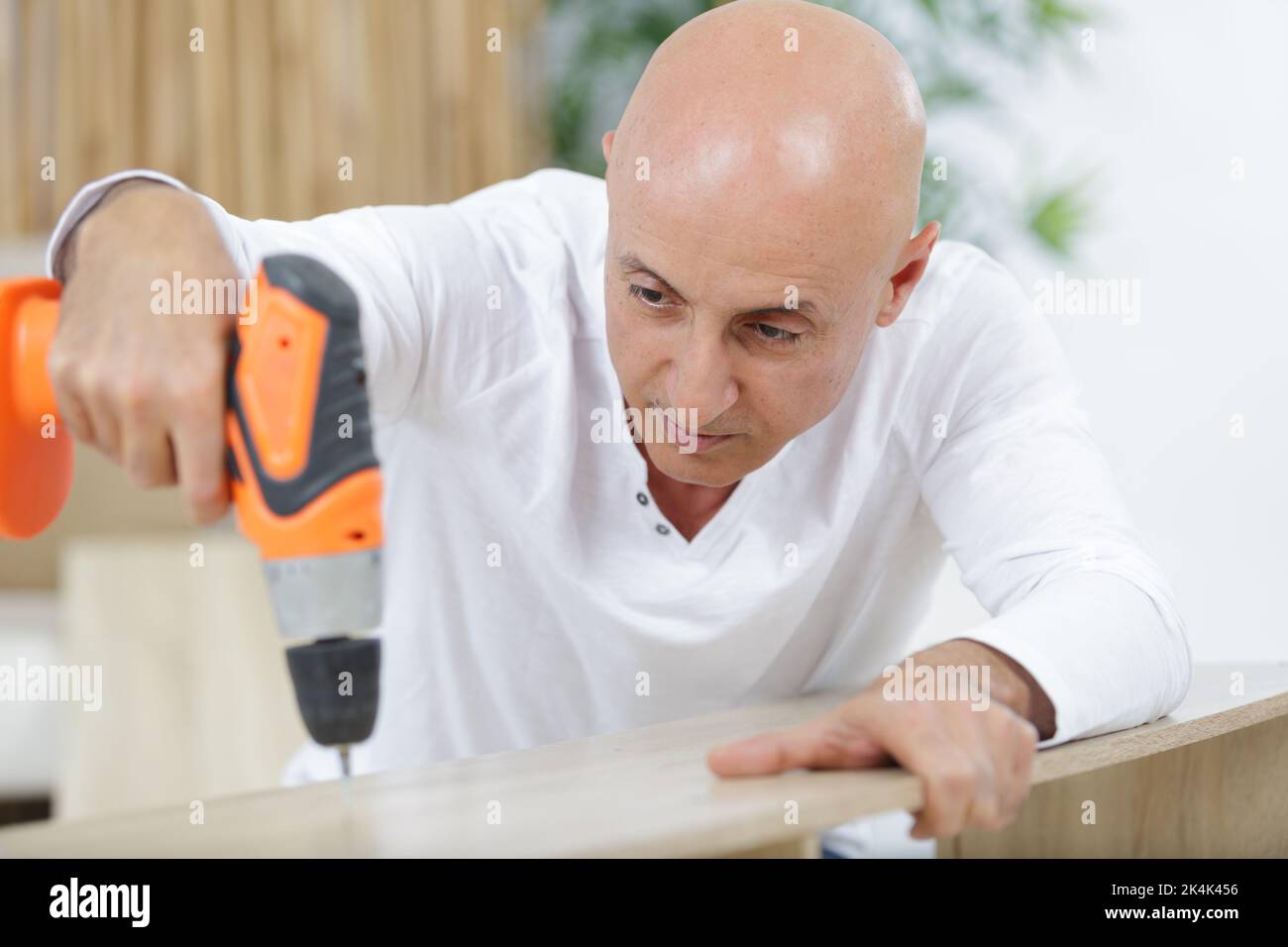 carpenter makes a hole in old wooden door Stock Photo