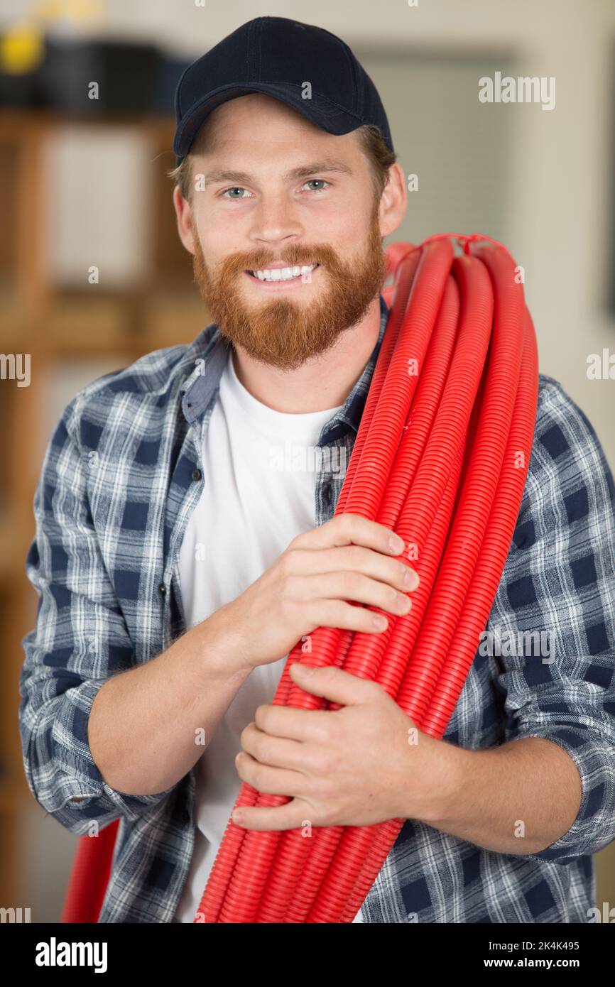 happy construction worker holding red pipes Stock Photo