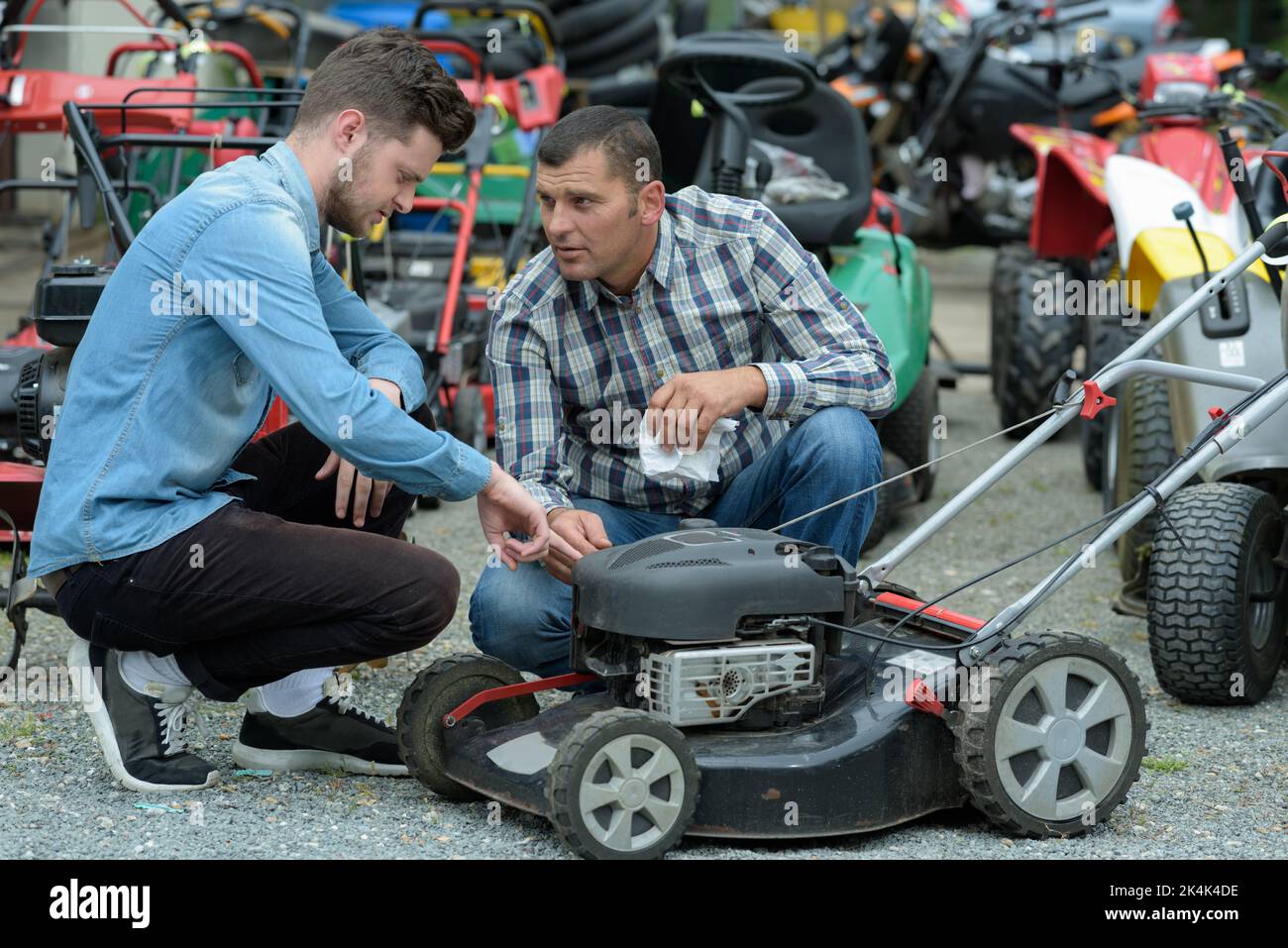 consultant shows a customer lawn mower in garden tools store Stock Photo Alamy