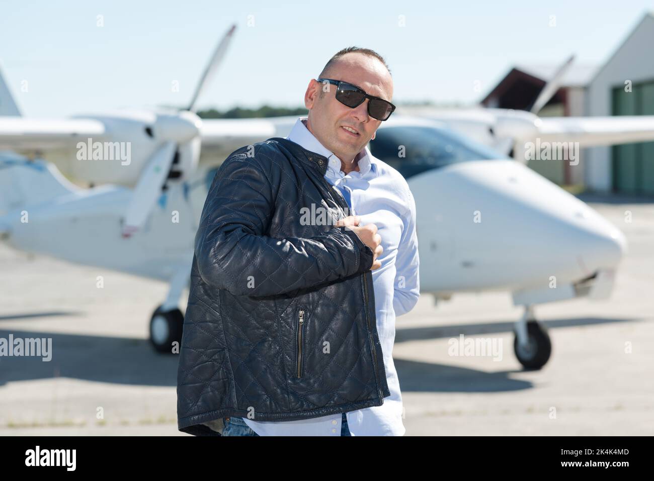 cool young pilot in sunglasses next to private jet Stock Photo