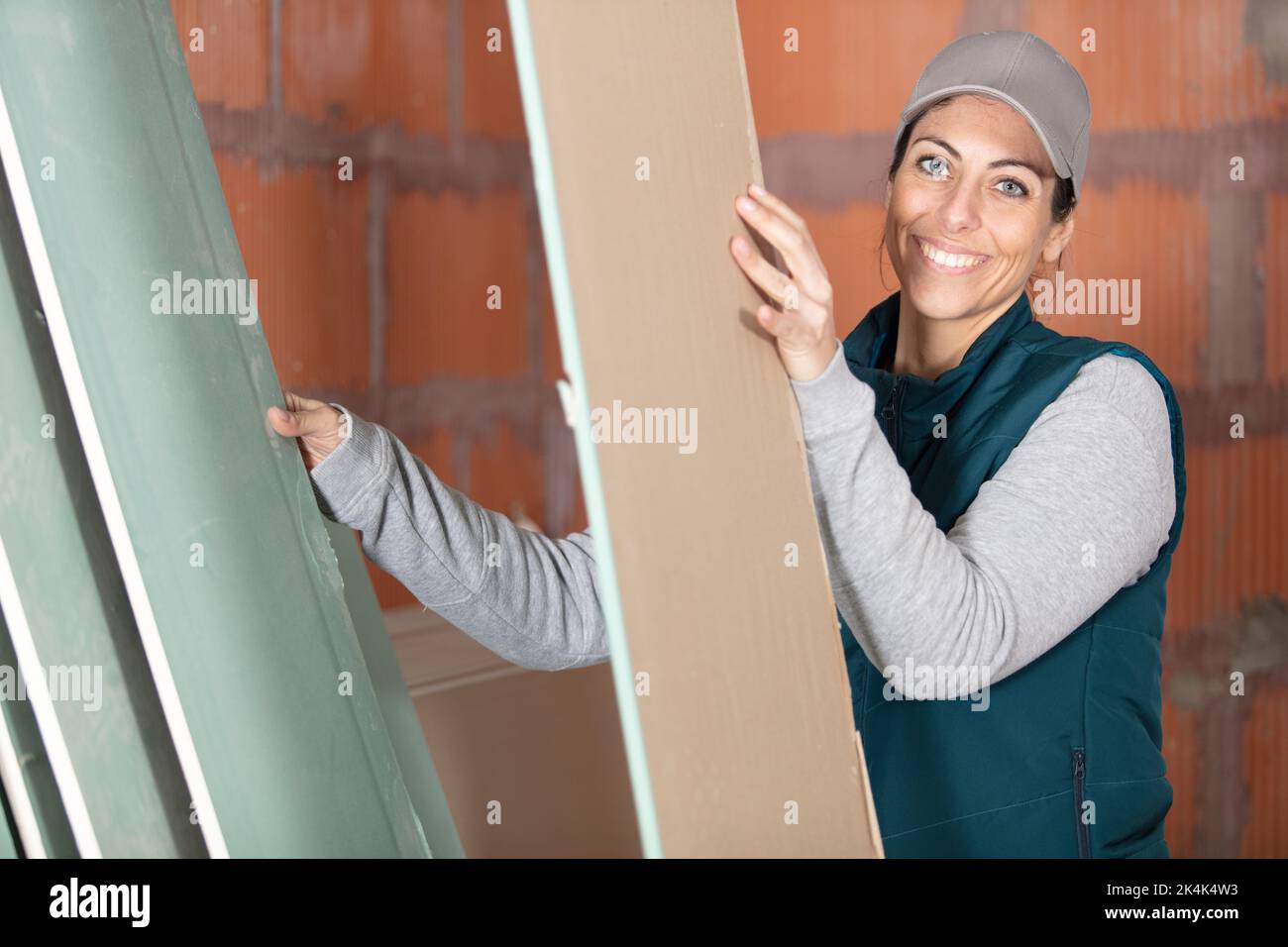 female worker carry styrofoam sheet insulation at construction site Stock Photo