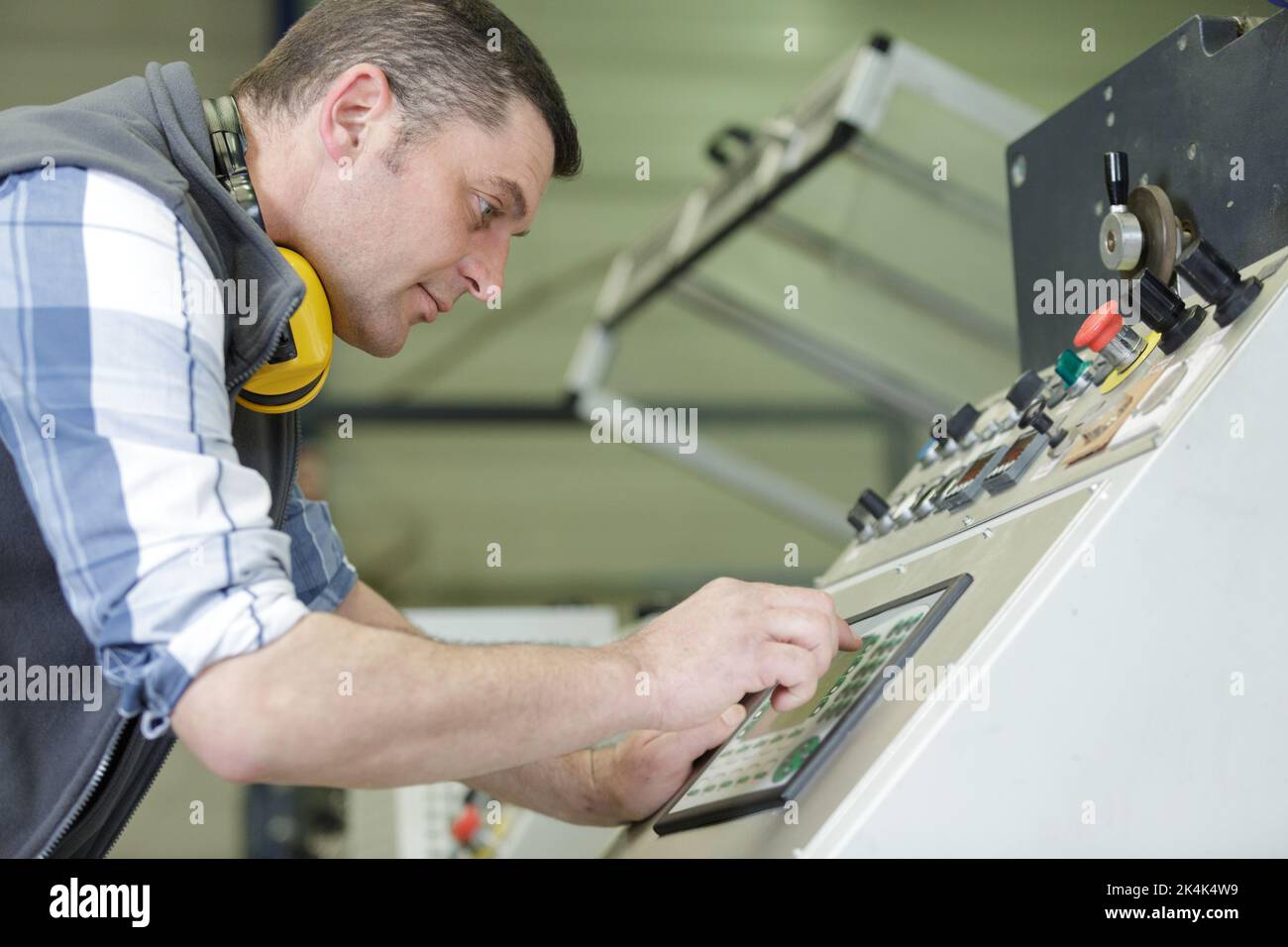 worker entering data in cnc machine at factory Stock Photo