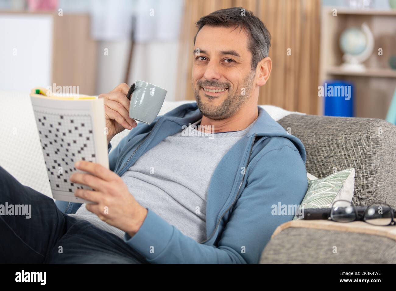 man is reading a magazine holding a cup of coffee Stock Photo