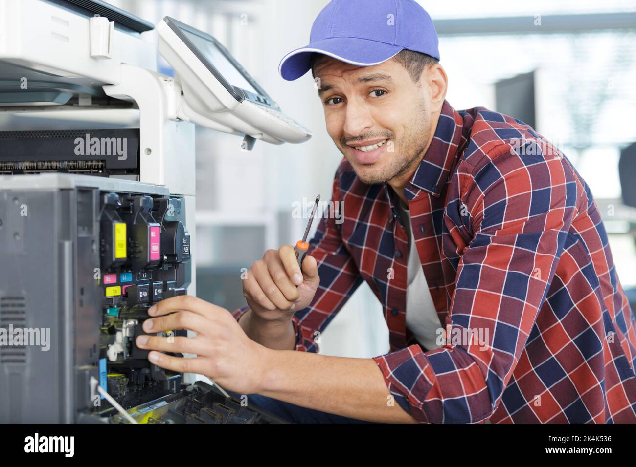 maintenance man with screwdriver checks photocopier ink Stock Photo