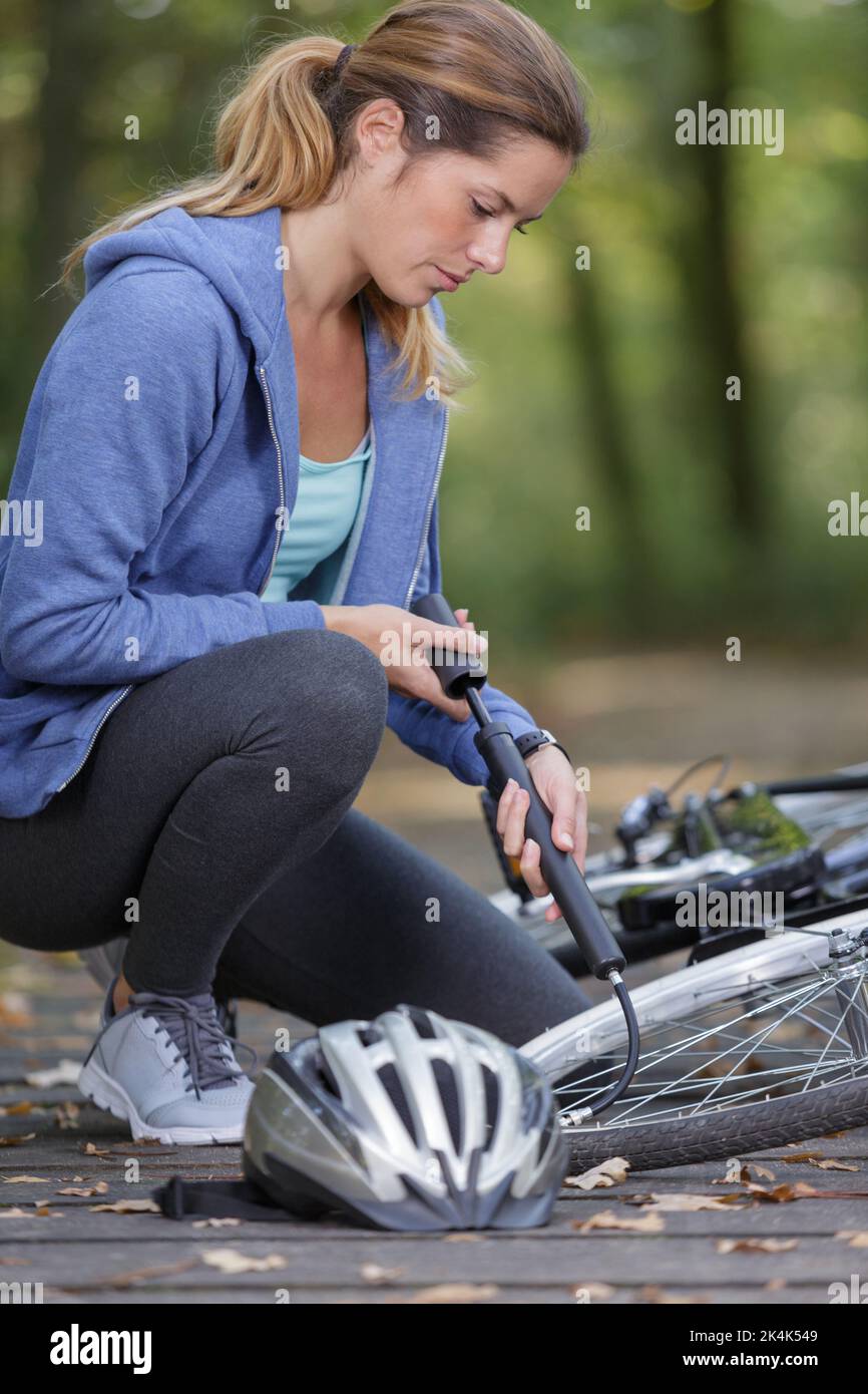 young woman pumps up the tire of her bike Stock Photo