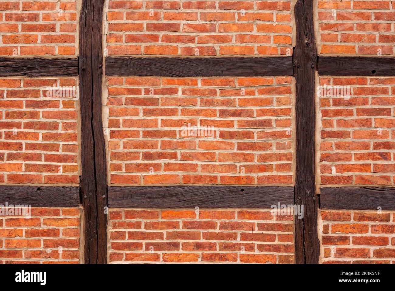 Background image showing a halftimbered wall made of brown wooden beams filled with red brick