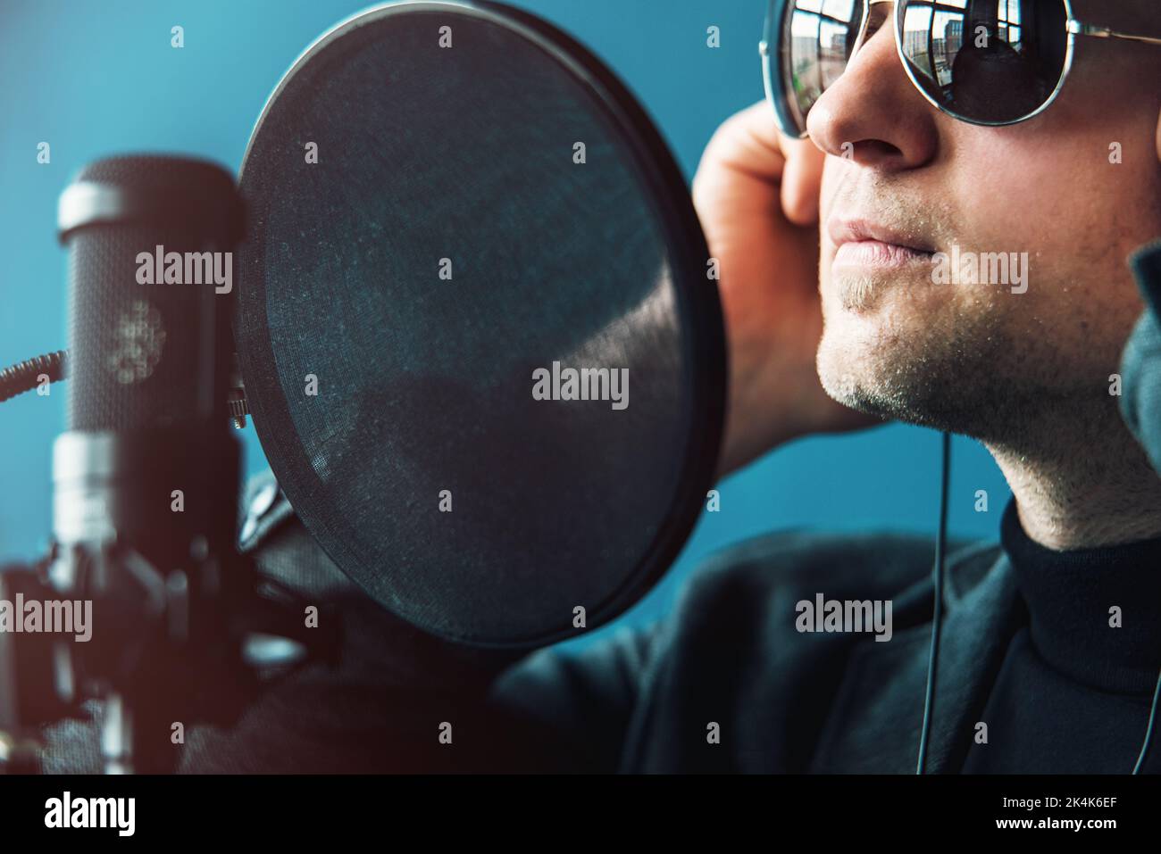 Close up of a man singer in a headphones recording a song in a home ...