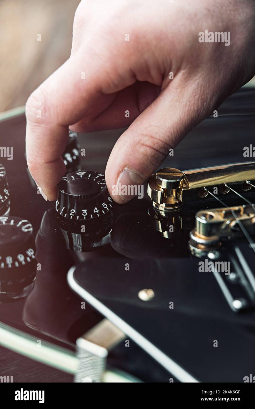 Male hand changing electric guitar settings. Tuning a timbre regulator