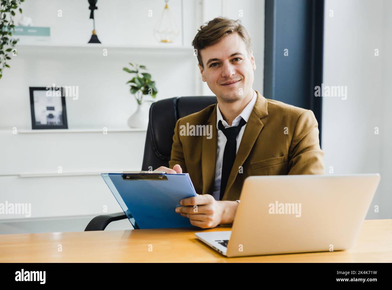 Smiling confident mature businessman leader looking at camera short note and sign on paper on table in office, happy and modern business man Stock Photo