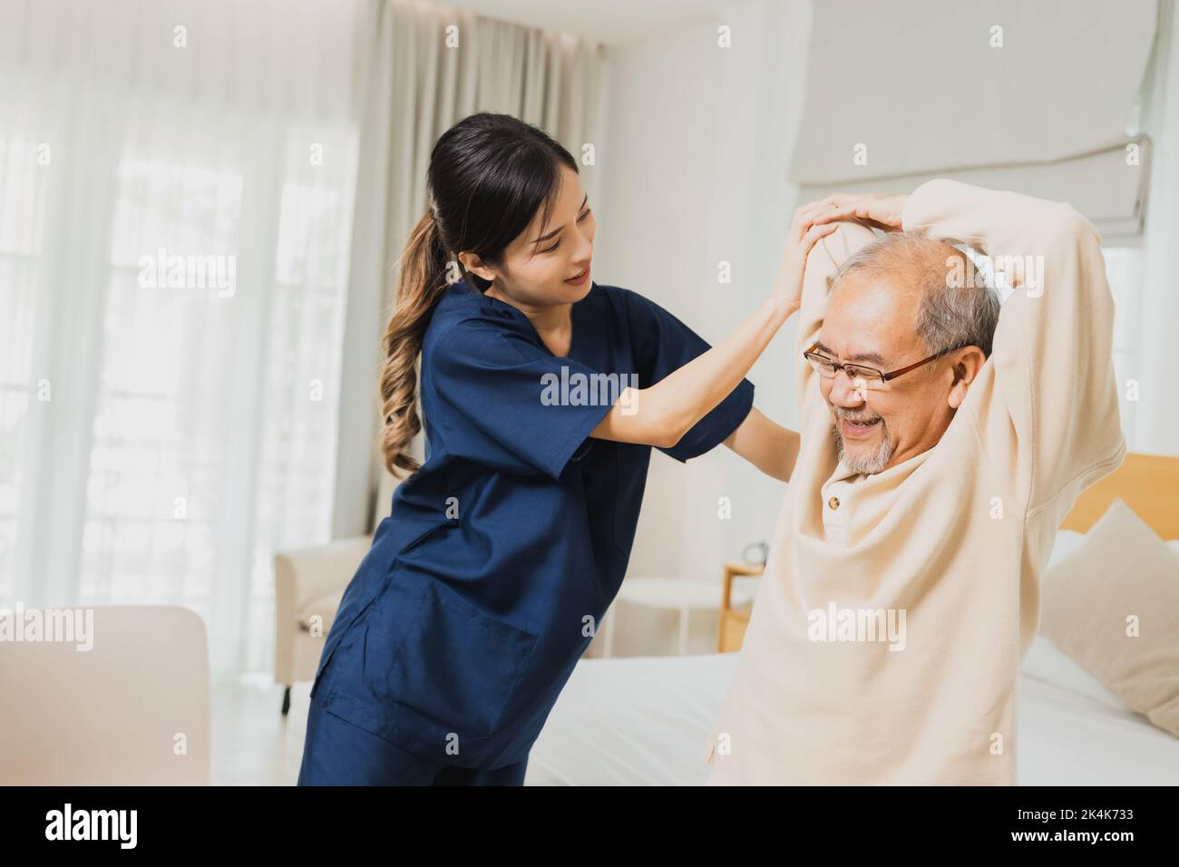 female physiotherapist helping senior man exercise, helping elderly