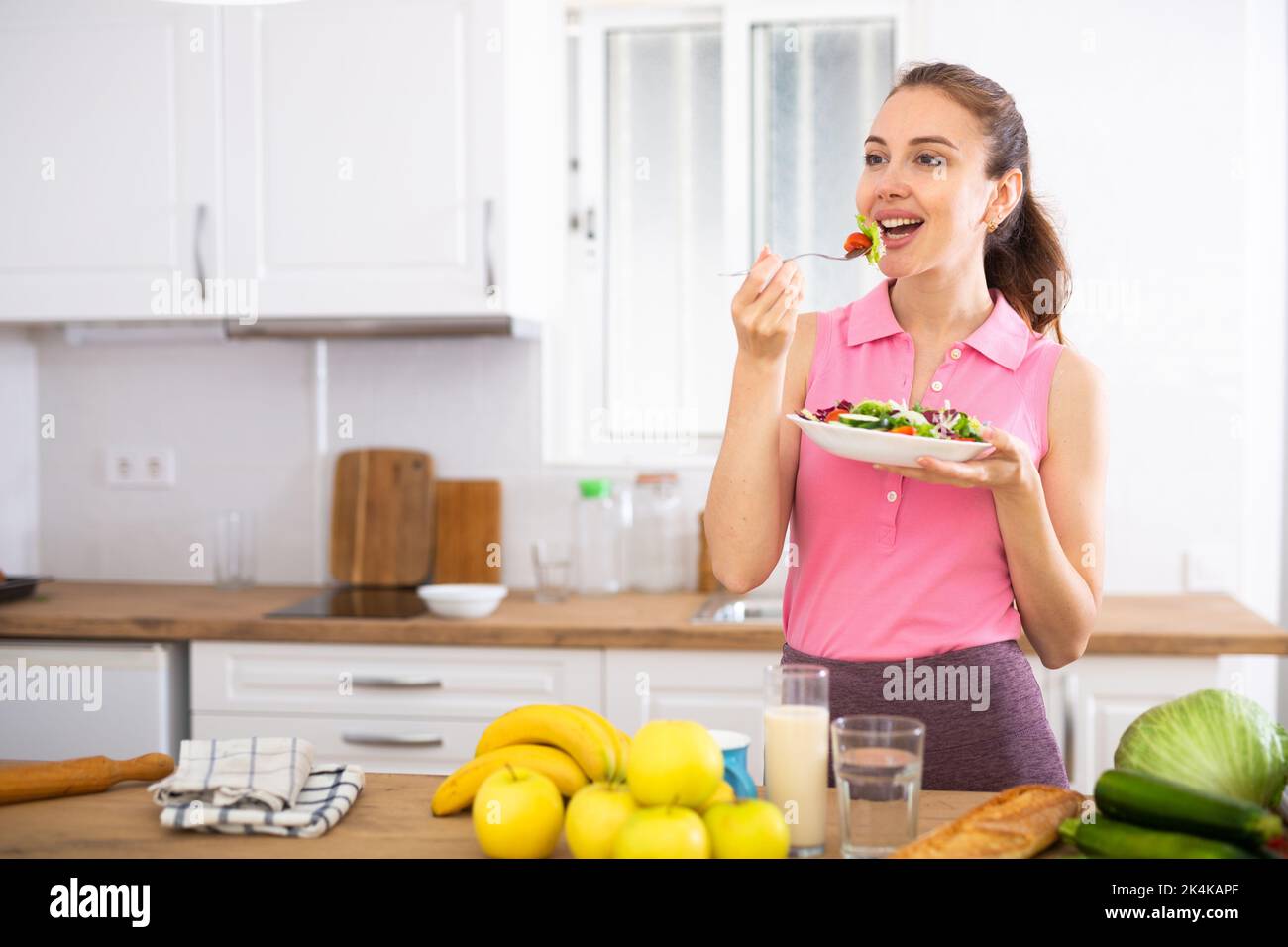 Cheerful woman eating vegetable salad at home Stock Photo
