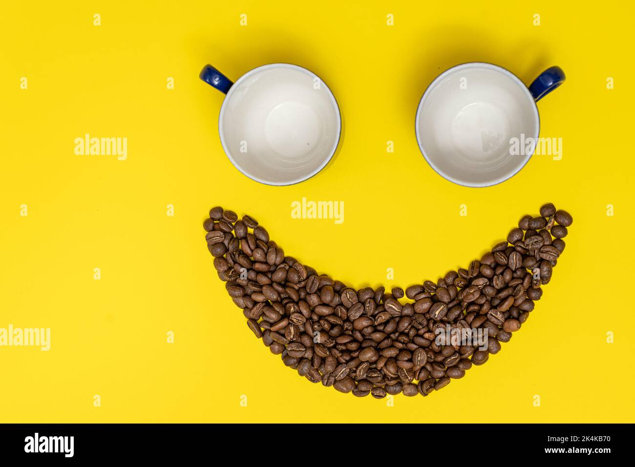 Happy emoticon made of coffee beans on a yellow background. Stock Photo