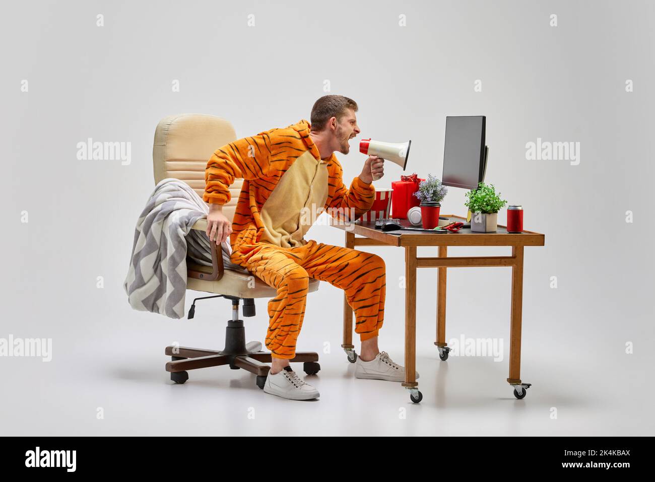 Young man in amazing costume shouting at megaphone at home. Colorful minimalism. Merry Christmas, New year holidays Stock Photo