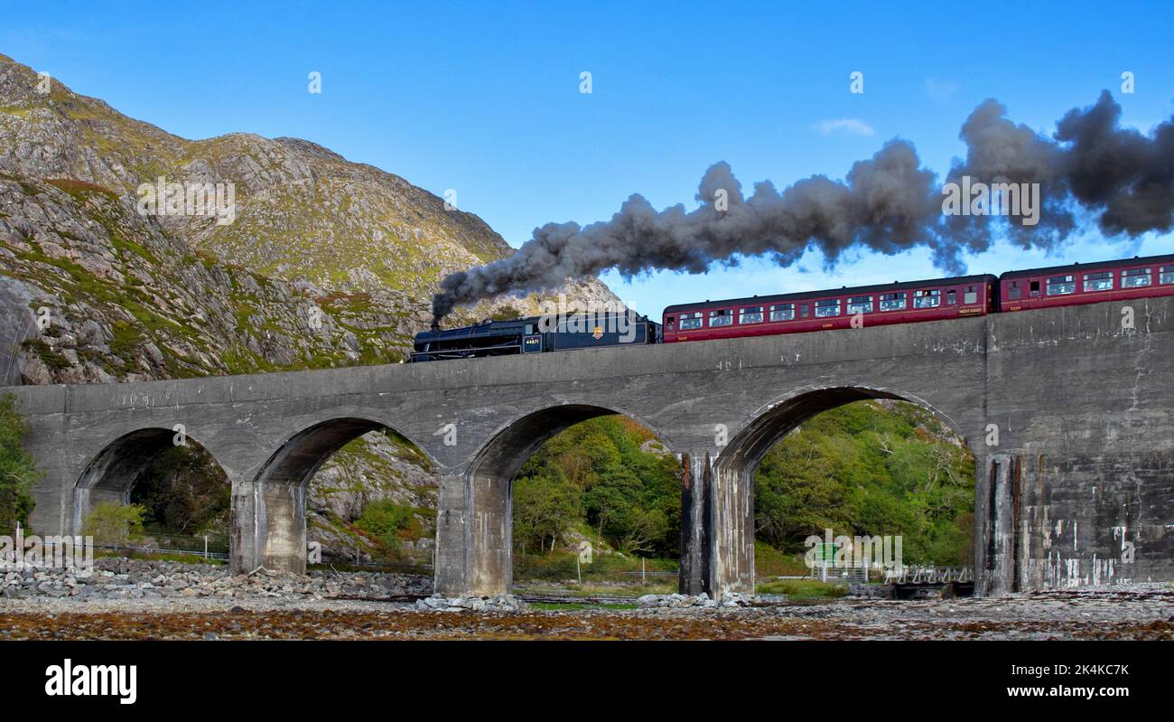 JACOBITE STEAM TRAIN DARK SMOKE FROM THE ENGINE AS IT CROSSES THE LOCH NAN UAMH VIADUCT Stock Photo