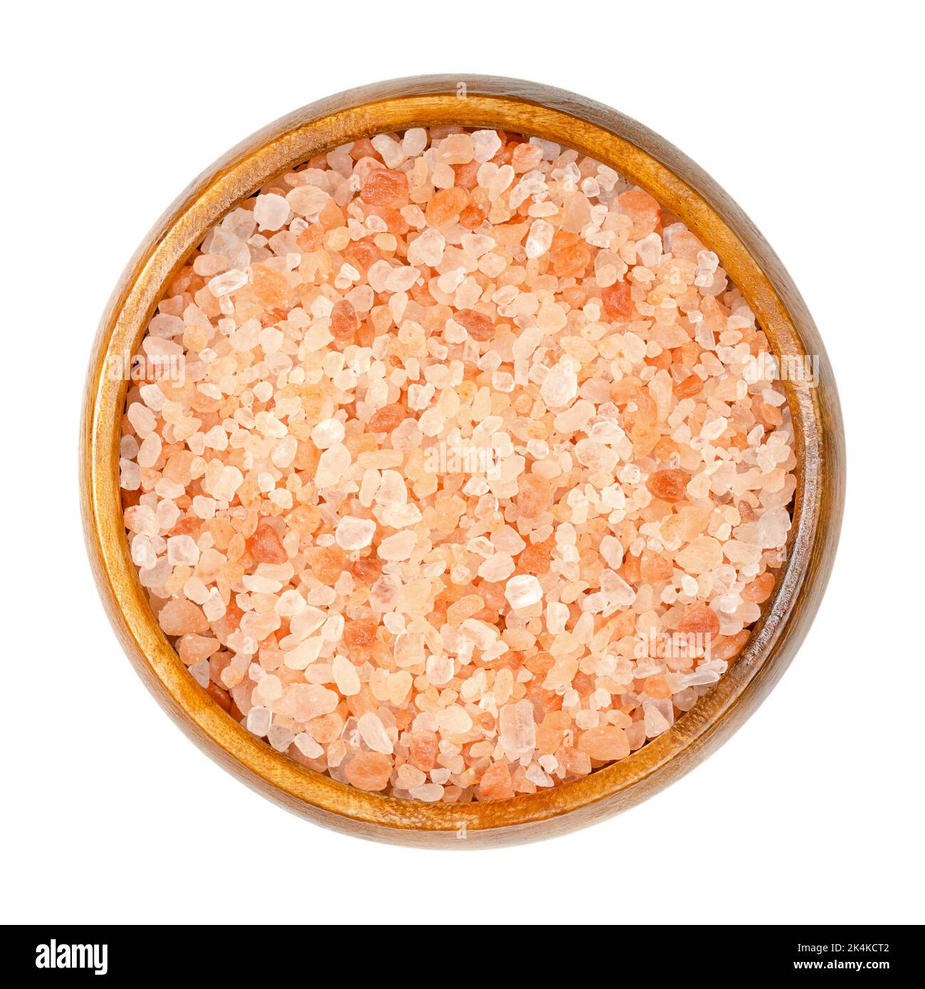 Himalayan salt, coarse crystals, in a wooden bowl. Rock salt, halite, with a pinkish tint, due to trace minerals, mined from the Punjab region. Stock Photo