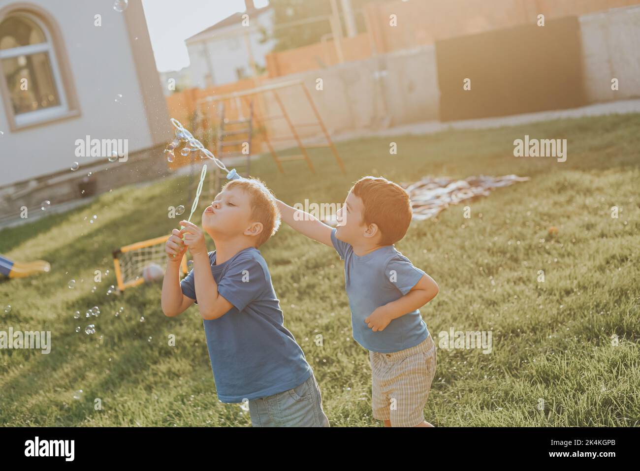 Two boys blow bubbles in the backyard. Summer lifestyle. Stock Photo
