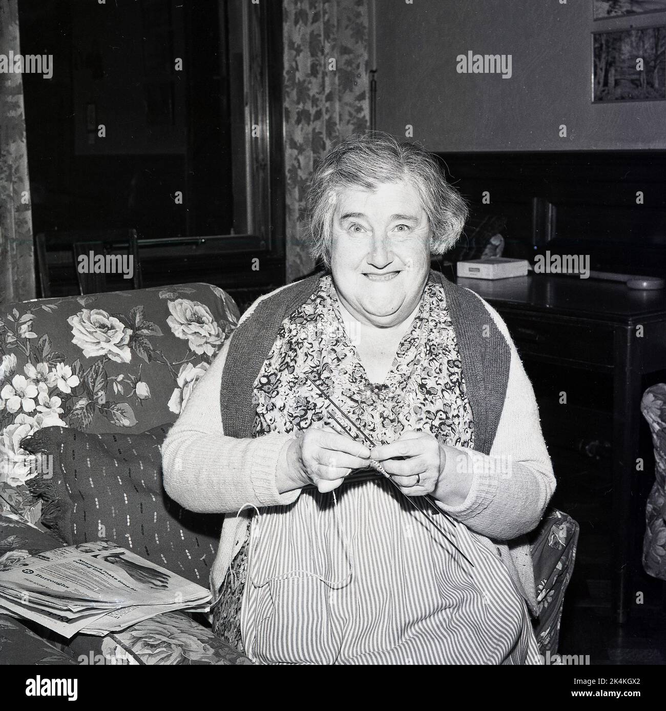 1965, historical, an elderly lady sitting, holidng her knitting needles, in an old peoples home smiling for a photo, Scotland, UK. Stock Photo