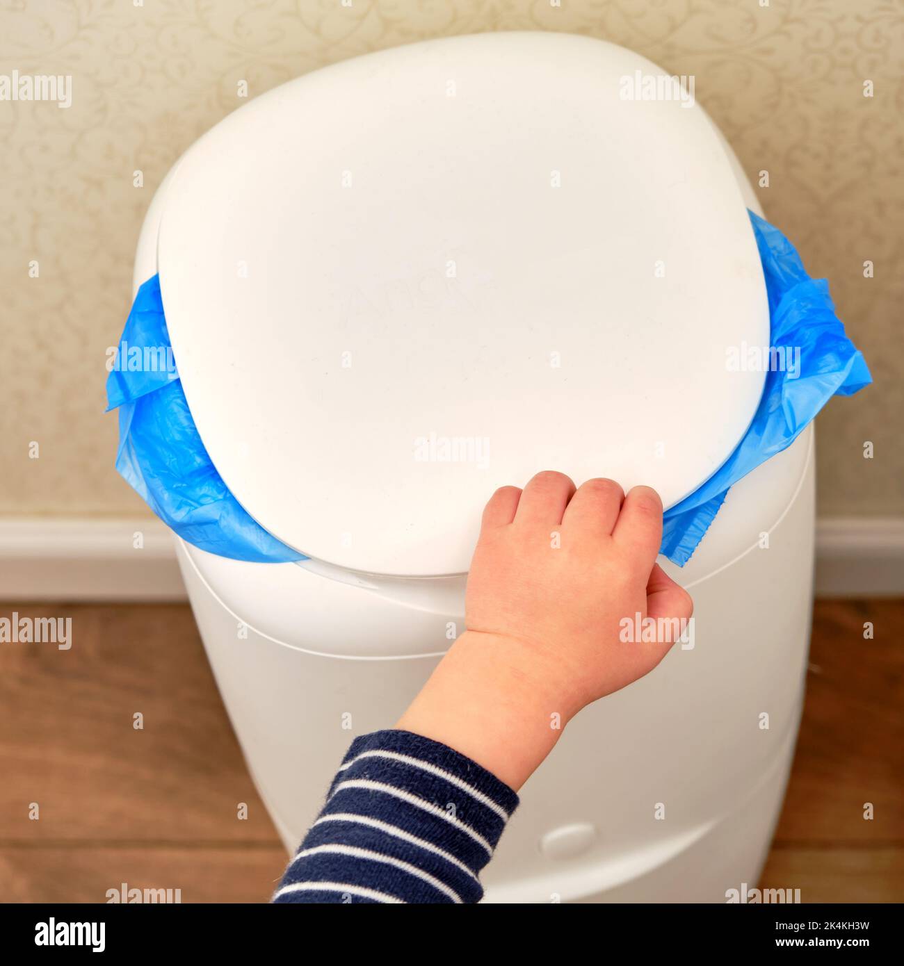 Child s hand opens the trash can, baby boy toddler throws out the trash. Kid aged one year and three months Stock Photo