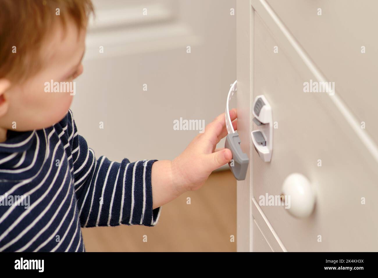 Baby opens the child lock on the closed drawer of the Toddler