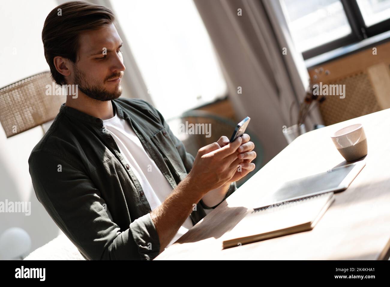 Young employee at workplace using mobile phone, checking social media ...