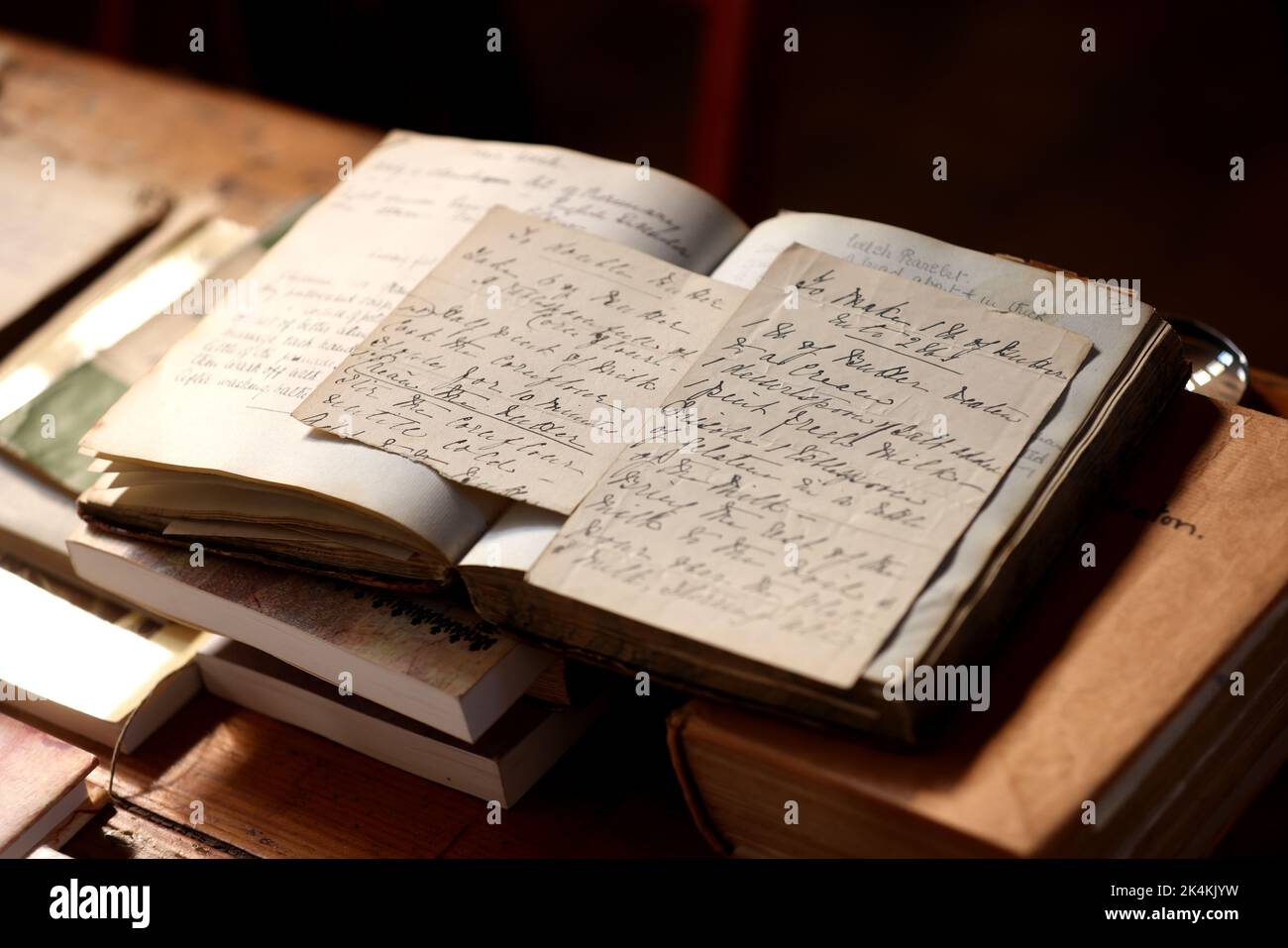 Old fashioned books and a magnifying glass showing hand writing from