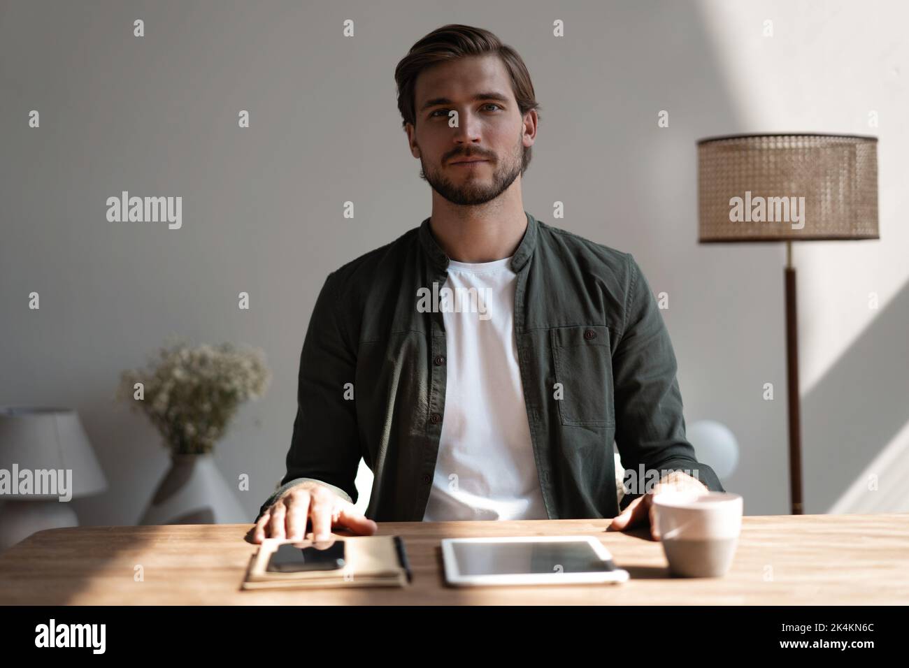 Good-looking millennial office employee sitting at desk smiling looking at camera. Successful worker, career advance and opportunity, owner of prosper Stock Photo