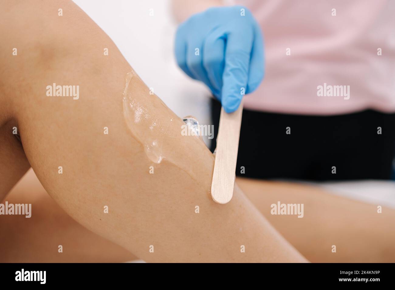 Woman beautician in blue glowes applies contact gel on the leg of a woman for laser hair removal in cosmetology studio. Close up Stock Photo