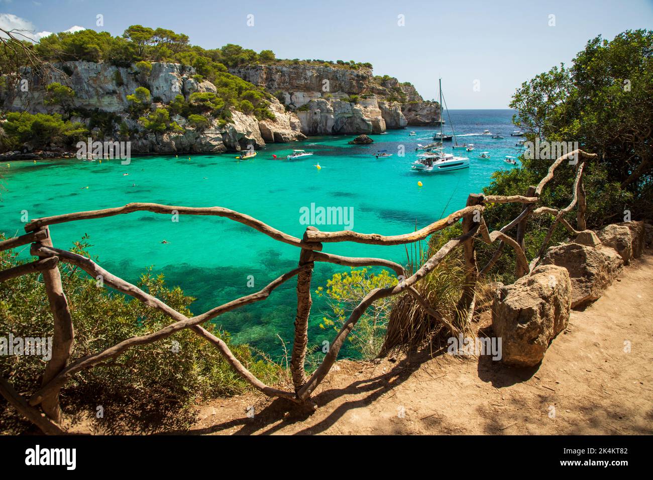 Menorca, Spain - September 1st, 2022: People enjoy swimming of the boats on Macarella beach Stock Photo