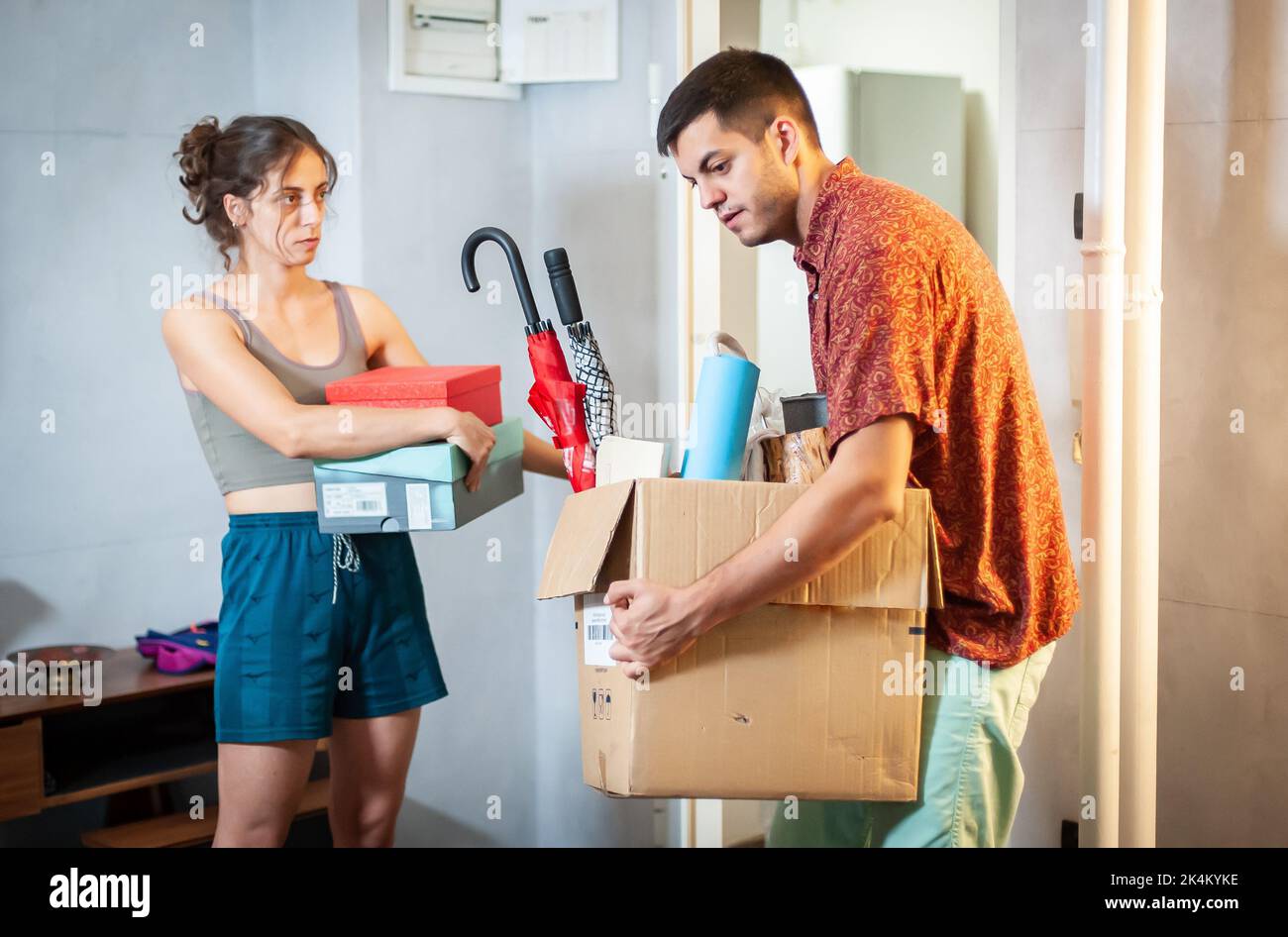 A young couple moves into their new apartment. They are surrounded by ...