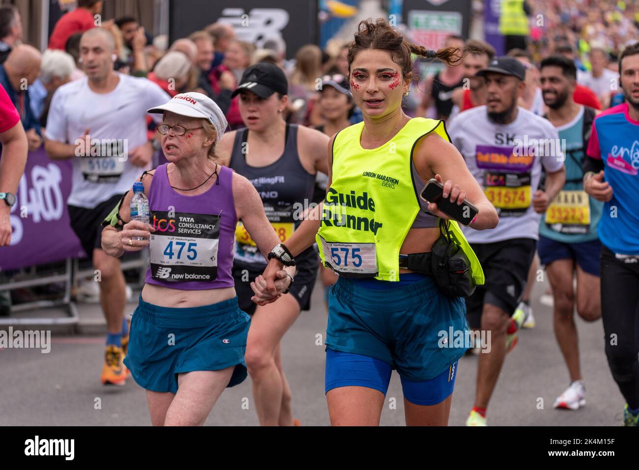 Visually impaired runner with guide runner running in the TCS London Marathon 2022, on Tower Bridge Approach road, UK. Lisa Thompson & guide Pappas Stock Photo