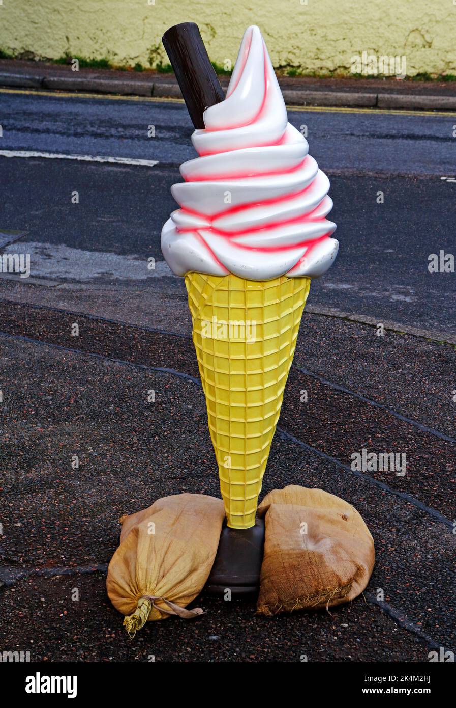 An ice cream advertising model sign stabilized by sandbags outside a shop in the main street at Mallaig, Morar, Scotland, United Kingdom. Stock Photo
