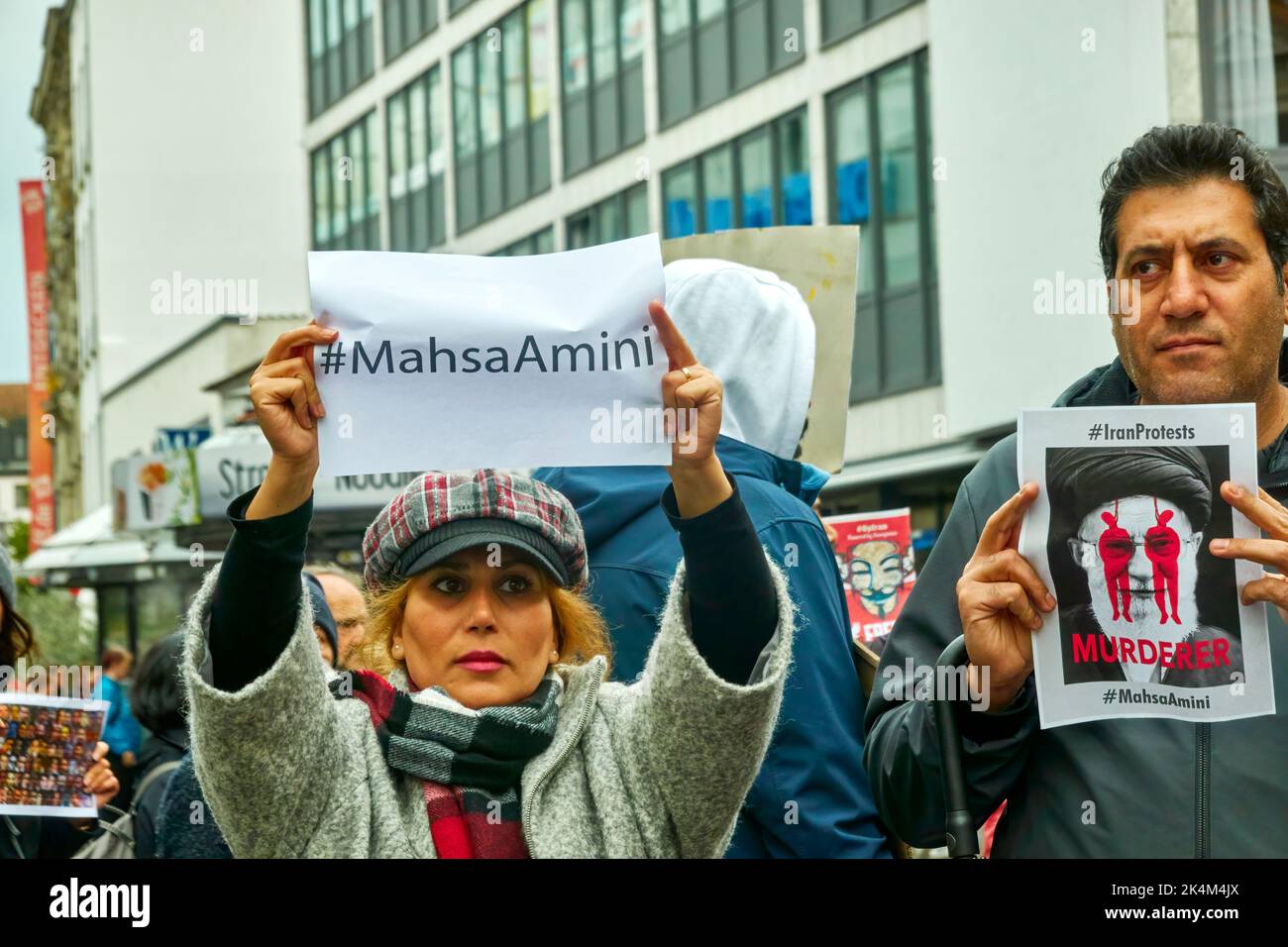 Braunschweig, Germany, October 1, 2022: Blonde woman holds up sign with hashtag to Mahsa Amini, next to man who dubs ayatholla a murderer Stock Photo