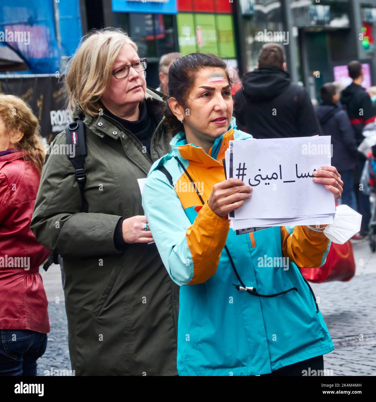 Braunschweig, Germany, October 1, 2022: Woman with Iranian flag made up holds up Persian hashtag to dead Mahsa Amini Stock Photo