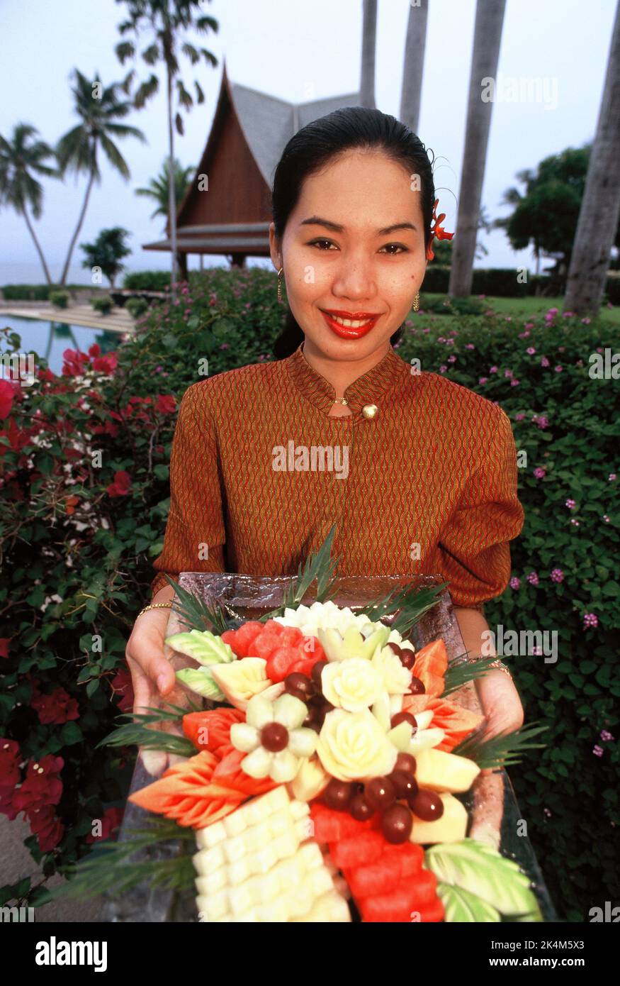 Thailand. Hua Hin. Chiva Som International Health Resort. Young Thai woman holding tray of traditional carved fruits. Stock Photo