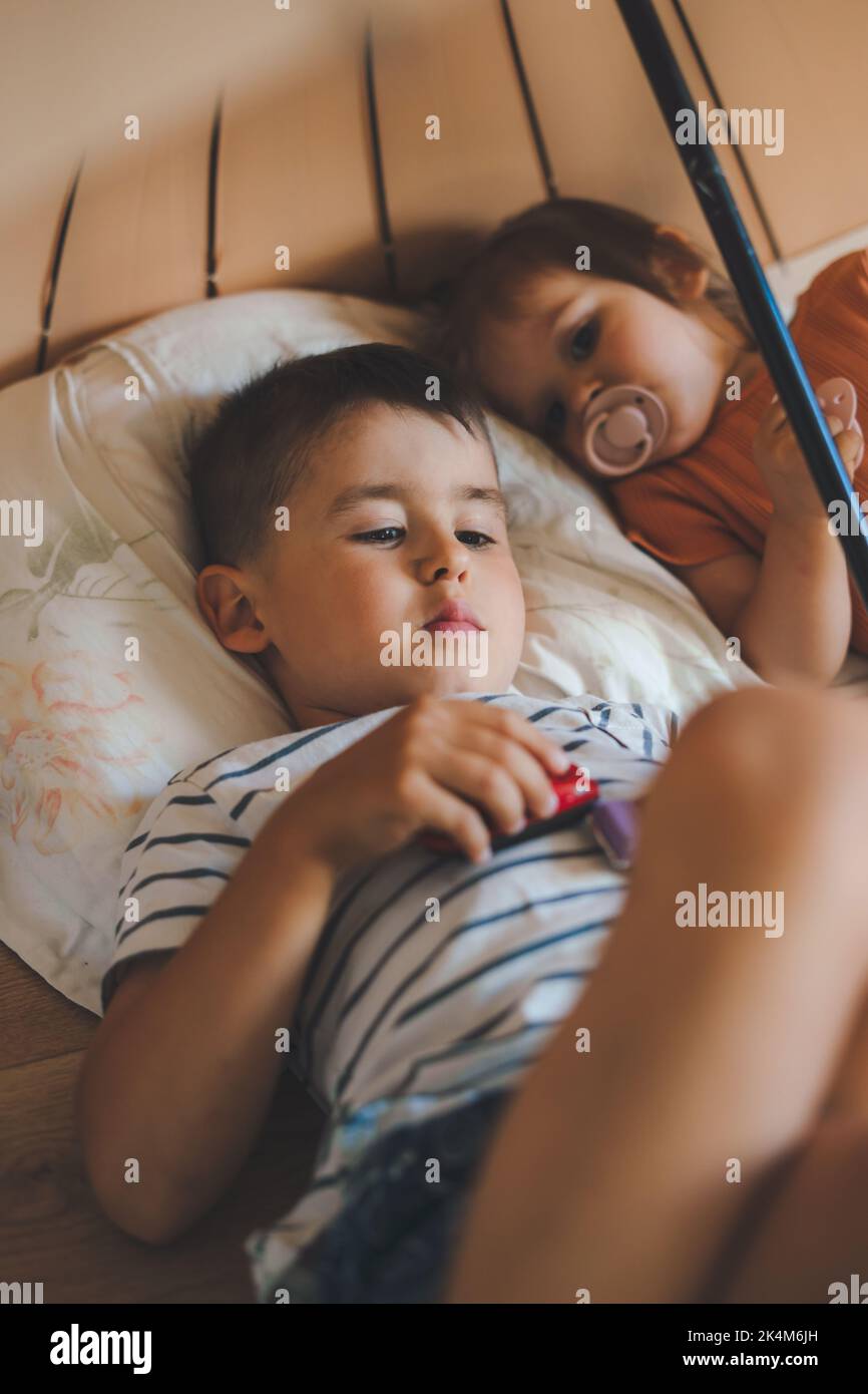 Two kids lying on the floor with pillows, relaxing under a umbrella