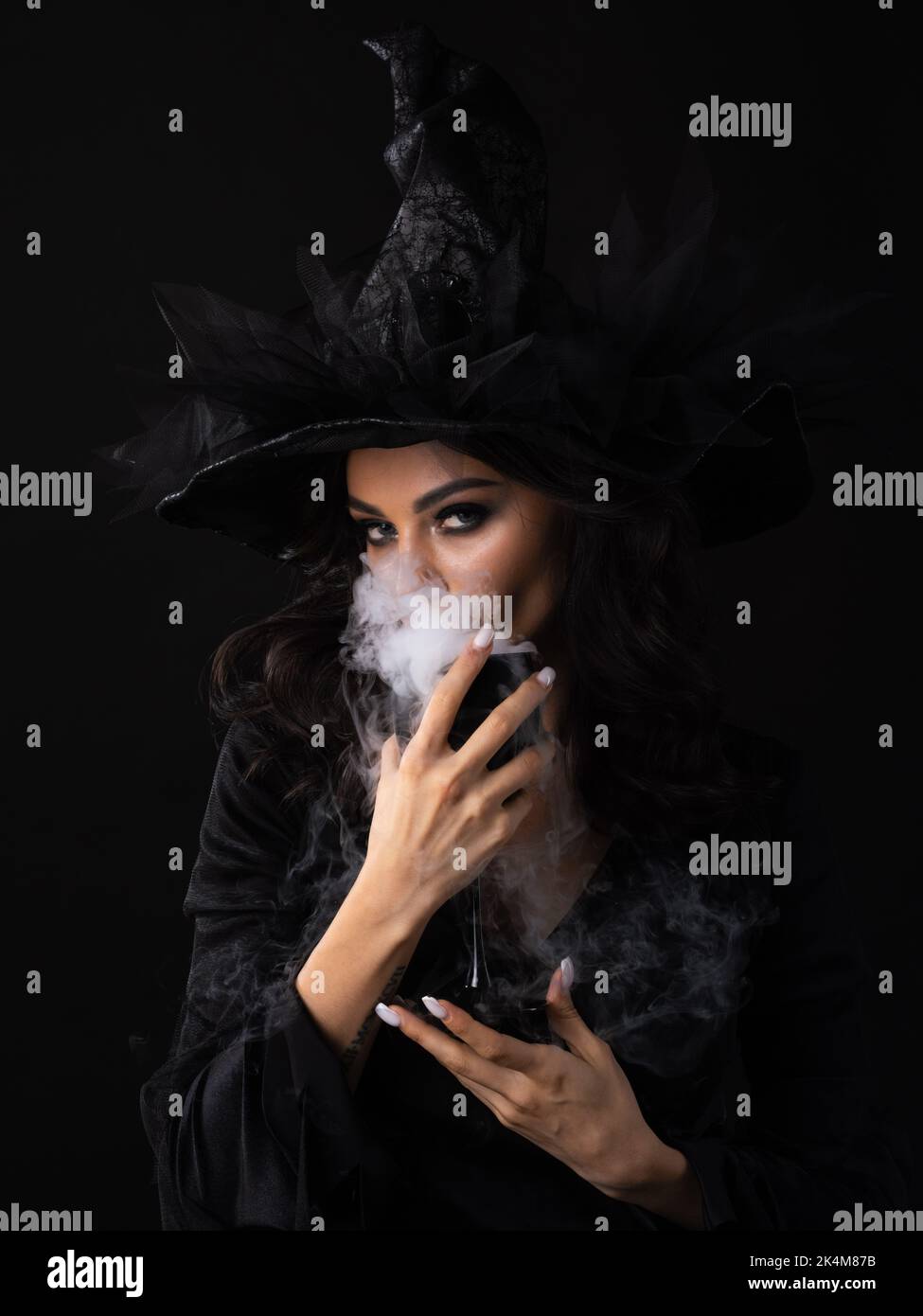 Halloween party woman in witch costume holding goblet of potion drink with smoke Stock Photo