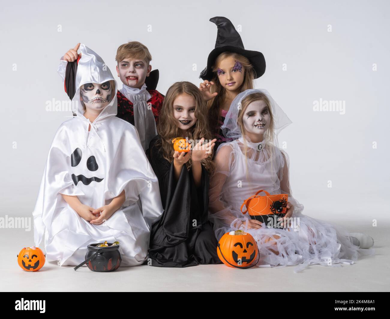 Group of children in costumes holding sweets at Halloween party Stock Photo