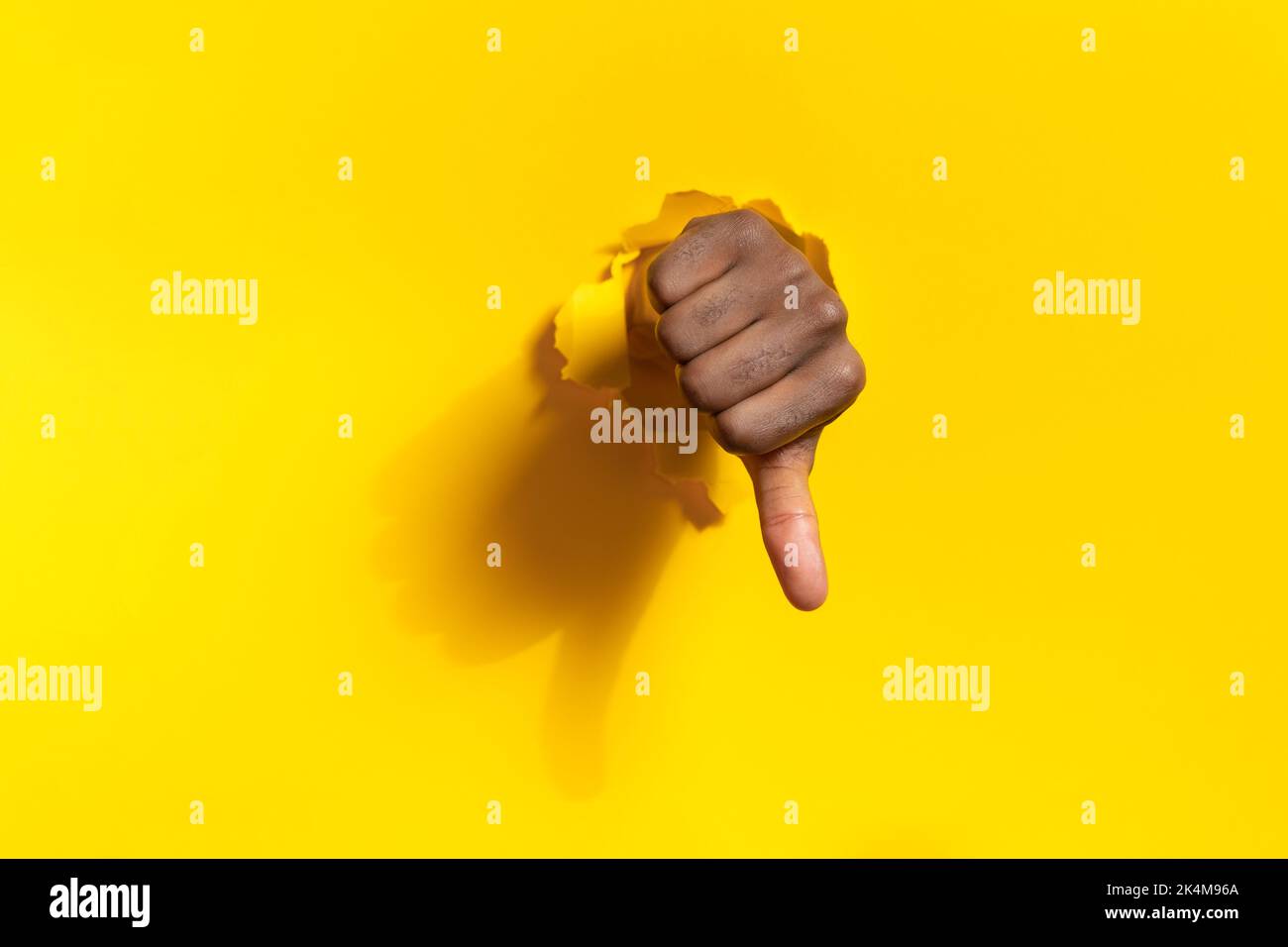 African american male hand showing thumb down through ripped hole in ...
