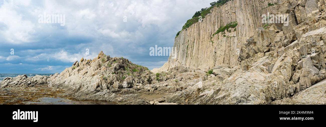 panorama with coastal cliff formed by solidified lava stone columns, Cape Stolbchaty on Kunashir island Stock Photo