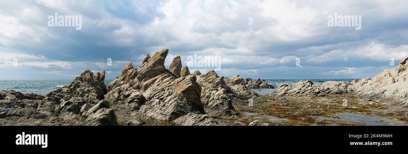 panoramic landscape with ocean shore with rocks formed by columnar basalt, Cape Stolbchaty on Kunashir Island Stock Photo