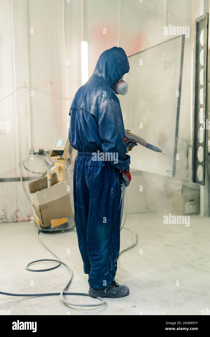 Perm, Russia - September 21, 2022: worker powder coats steel parts in a spray booth Stock Photo