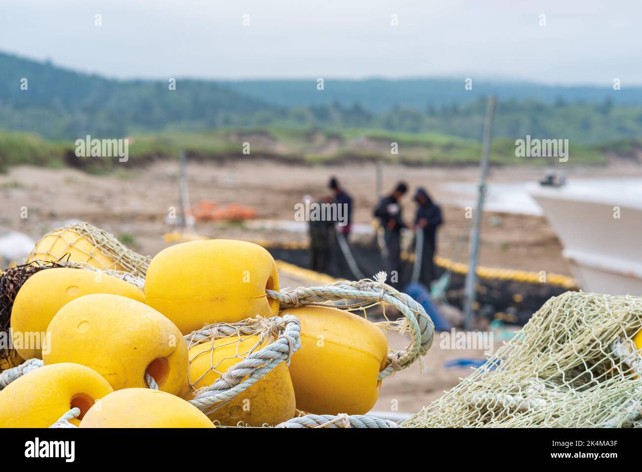 industrial fishing nets with bright floats is folded ashore against the background of fishermen checking the trawl Stock Photo