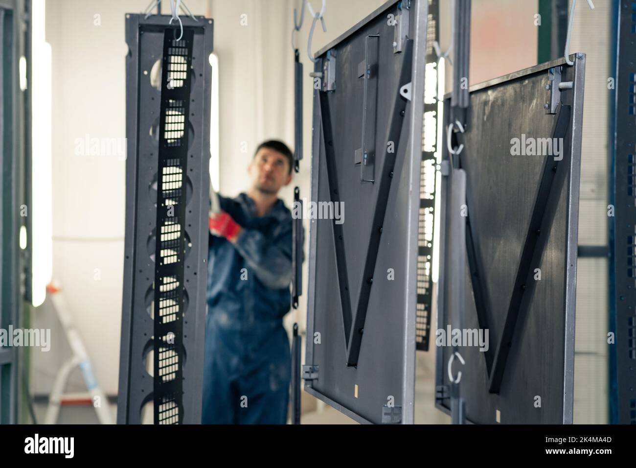 Perm, Russia - September 21, 2022: worker moves metal parts to a powder coating booth Stock Photo