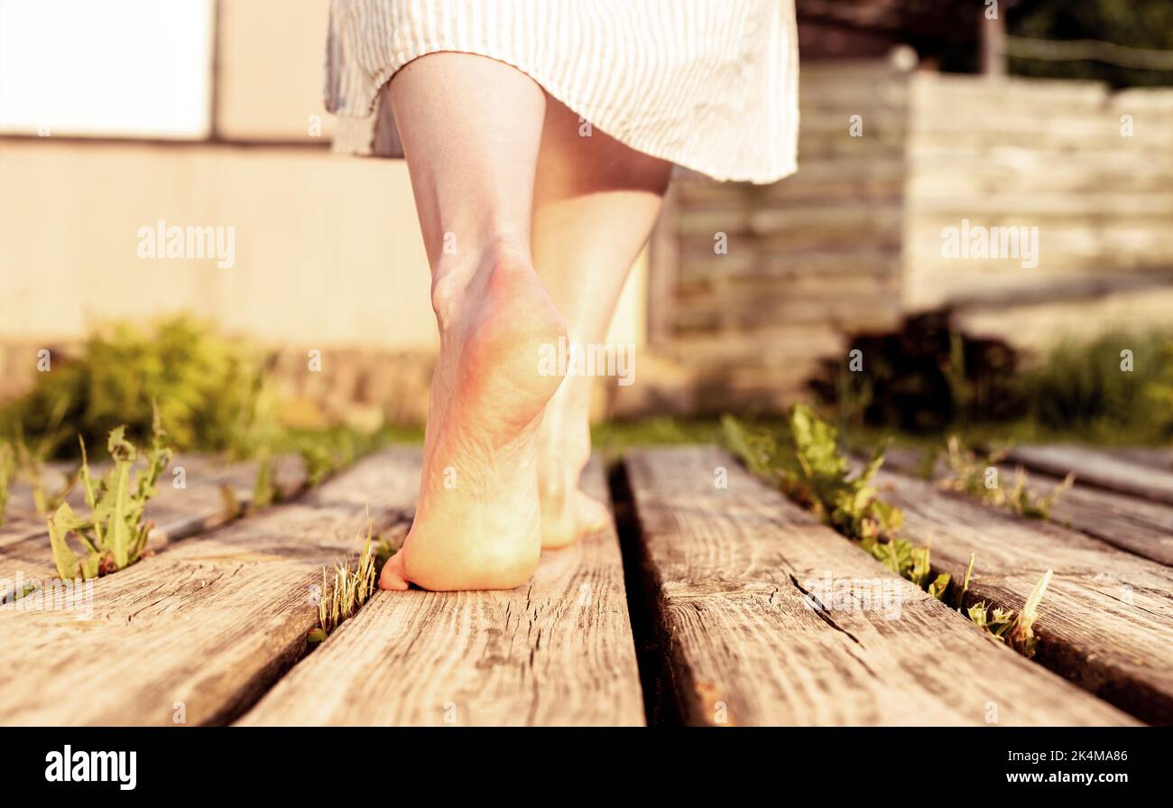 Girls feet walking on wood planks in nature. Women barefoot legs going outdoors. High quality photo Stock Photo