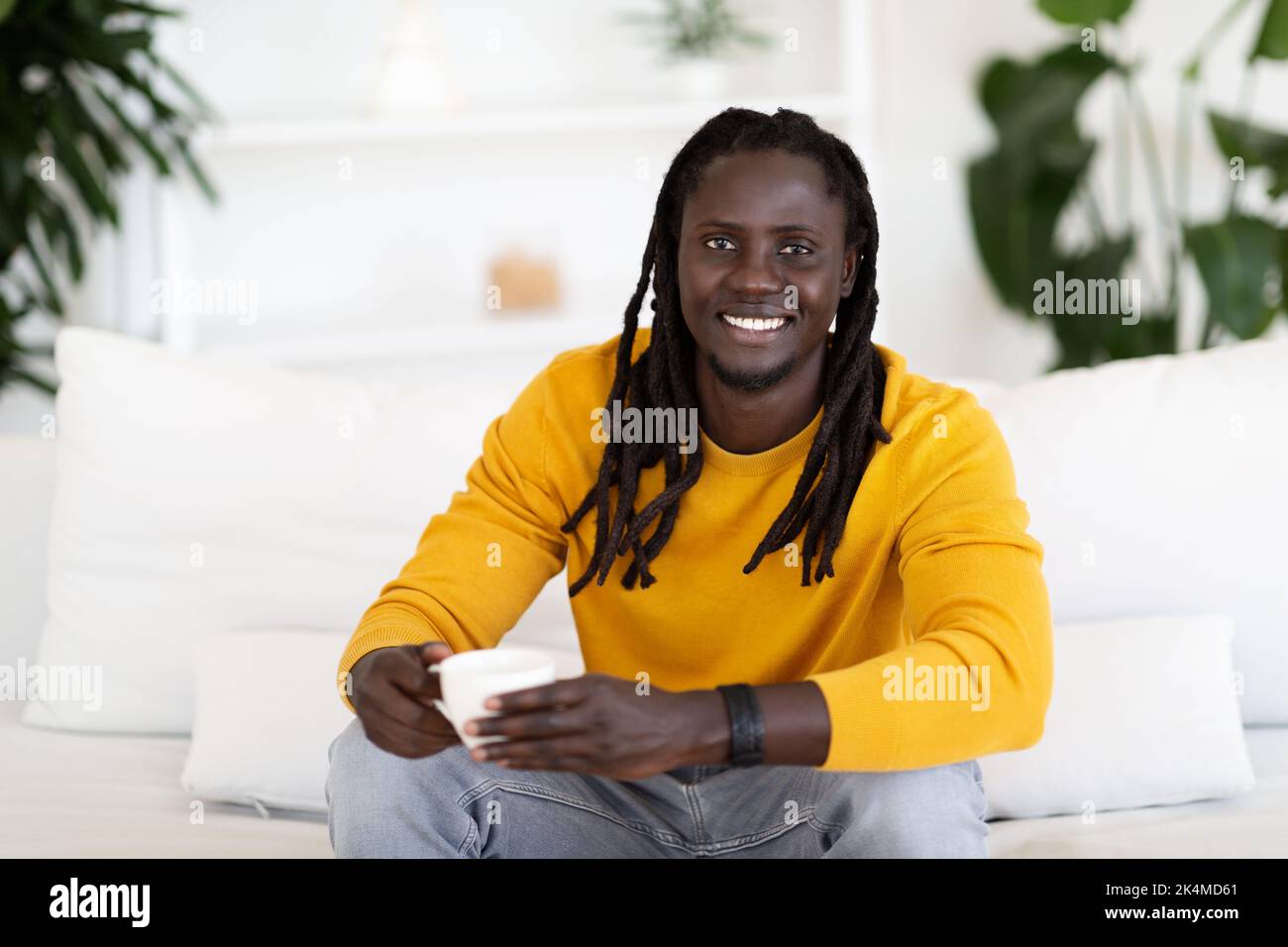 Handsome Young Black Man Drinking Coffee While Relaxing On Couch At Home Stock Photo
