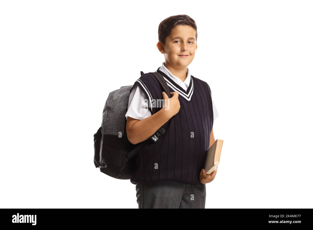 Schoolboy in a uniform holding a book and carrying a backpack isolated ...