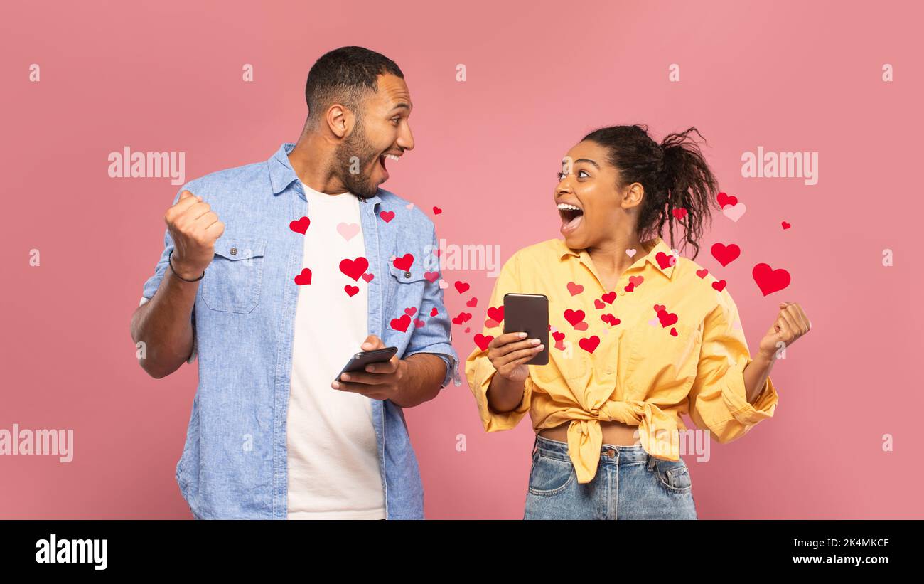 Excited young black couple using mobile phones and gesturing Stock Photo