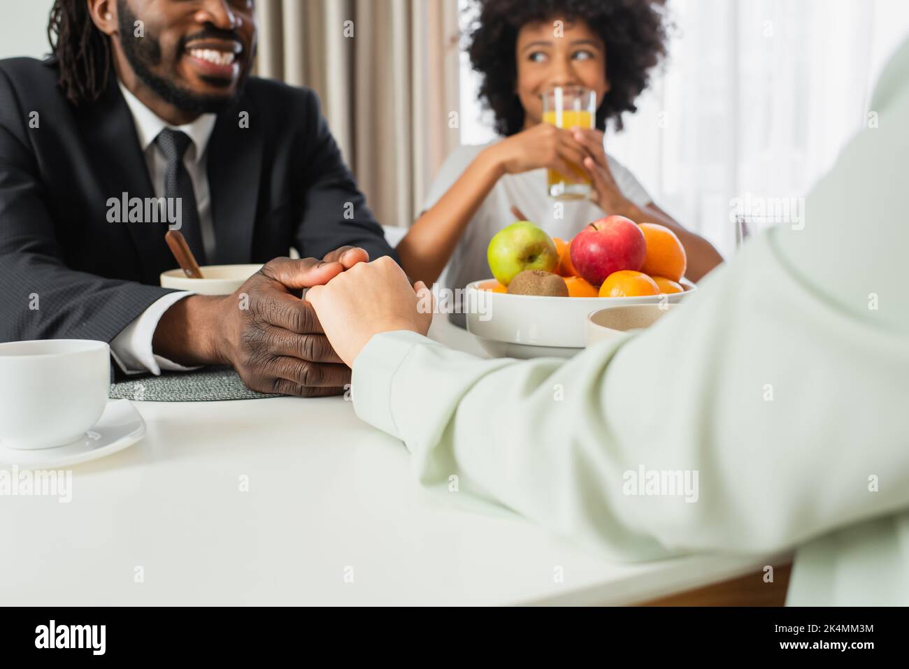 happy african american man in suit holding hands with wife near ...